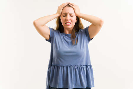 Pretty woman in agony rubbing her head while having a strong migraine. Woman in her 20s with a...