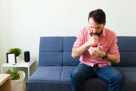 Sick adult man coughing blood because of respiratory problems. Latin man sick with pneumonia illnessの写真素材
