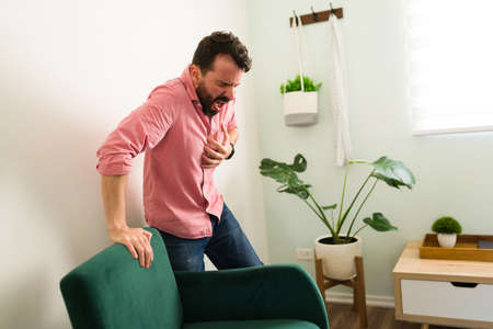 Sick man having a heart attack while alone at home. Man with a cardiovascular disease needs to go to the emergency roomの写真素材