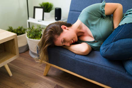 Suffering young woman suffering from appendicitis and having a lot of pain in her stomach while...