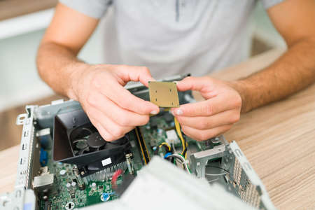 Close up of the technician's hands holding a microprocessor. Young man repairing a computer hardware