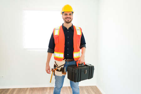 Portrait of a happy contractor in his 30s smiling and wearing a safety helmet, an anti-reflective...