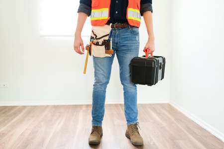 Professional engineer or contractor wearing a belt with tools and carrying a toolbox during his work dayの写真素材