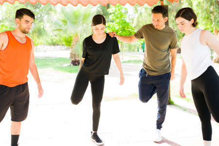 Doing a warm-up. Beautiful group of friends stretching their legs and warming up before starting their workout routineの写真素材