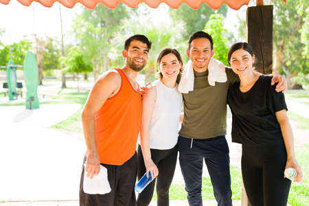 Portrait of an active group of friends in activewear hugging and looking at the camera for a photo before their cardio workout outdoorsの写真素材