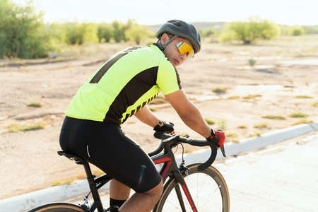 Male athlete pedaling on his road bike. Latin professional cyclist looking at the camera while...