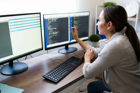 Attractive woman working on programming software app. Young woman coding and checking her work on...
