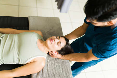 High angle of a beautiful young woman receiving a neck and head massage from a professional latin...