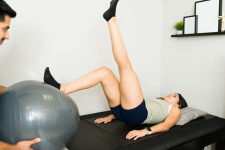 Beautiful young woman doing rehabilitation exercises to regain strength on her muscles at the...