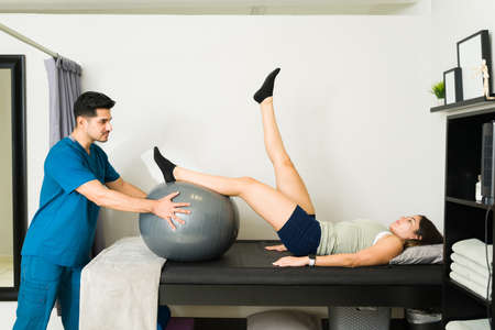 Caucasian female patient doing physical therapy due to a leg injury with a male physiotherapistの写真素材