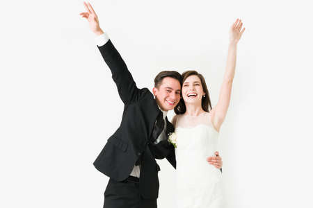 Cheerful couple laughing and raising their arms after the ceremony. Bride and groom celebrating at their wedding receptionの写真素材