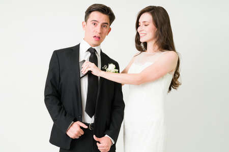 Attractive caucasian woman taking the wallet from her groom. Young wife spending money from her suprised husbandの写真素材