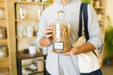 Close up of a male customer shopping herbal teas at an alternative bulk shop. Young man buying tea...