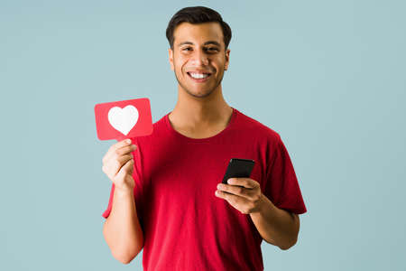 Looking for love. Cheerful man making eye contact and feeling happy while using dating apps on his...