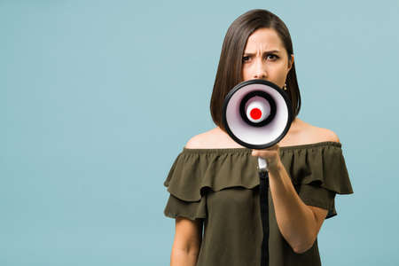 That is an injustice. Worried young woman holding a megaphone and talking loud about her problemsの写真素材