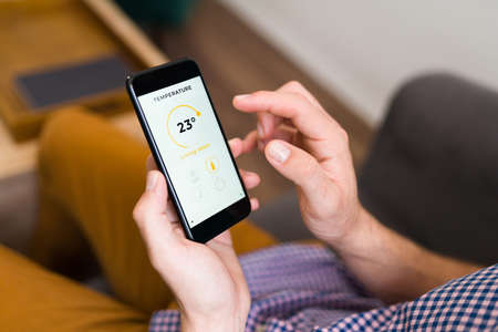 Male hands looking at the weather app on his smartphone. Adult man checking if it's going to rainの写真素材