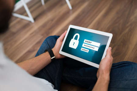Young person typing his username and password to login into an online account on his tablet
