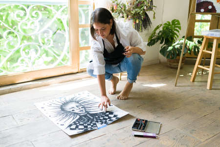 Young woman finishing a charcoal portrait at an art workshop. Beautiful painter ready to frame an...