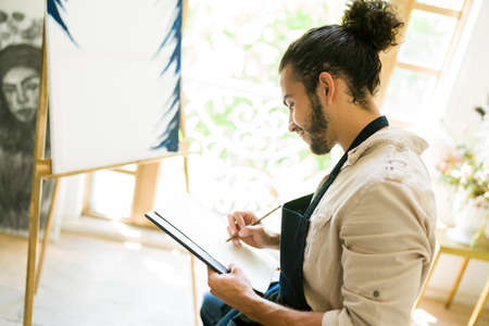 Sketching a new painting. Creative young man doing a sketch before creating a new oil painting