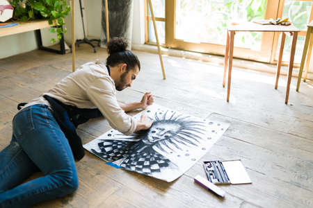 Creative painter young man relaxing during a leisure day and drawing an artistic charcoal portraitの写真素材