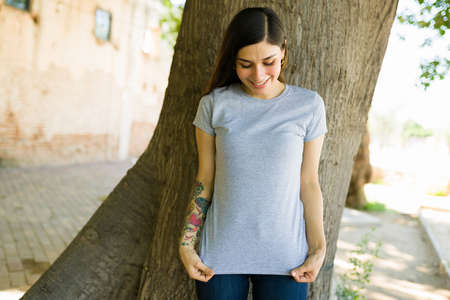 Look at this beautiful design. Happy woman showing the print on her gray t-shirtの写真素材