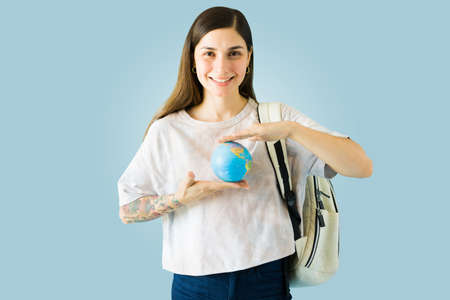 Smart college student holding a globe between her hands and ready to go on an exchange program