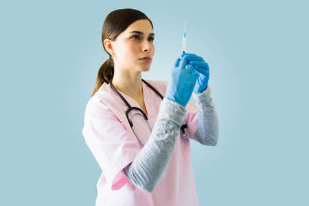 Professional young woman and nurse with blue gloves holding a syringe and about to give a vaccine...
