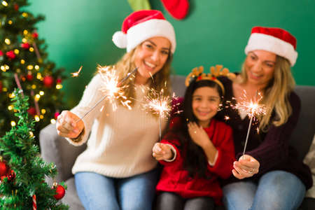 Close up of a multiracial young family having fun with a sparkler during the Christmas holidayの写真素材