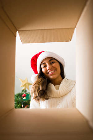 I love my presents. Cheerful young woman opening a Christmas gift and looking inside while smilingの写真素材