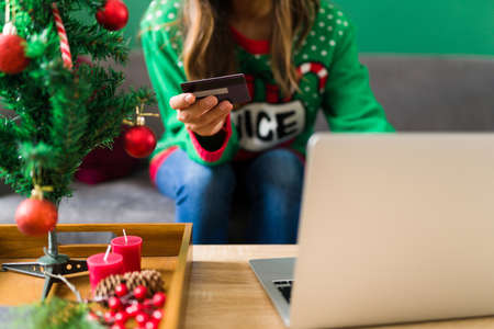 Close up of a young woman doing online shopping and using her credit card to pay for the christmas giftsの写真素材