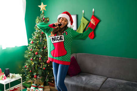 Having fun with karaoke. Super happy woman singing while listening to music during Christmas at home