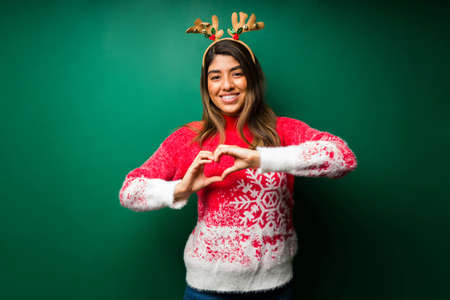 I love Christmas. Attractive woman making a heart gesture with her handsの写真素材