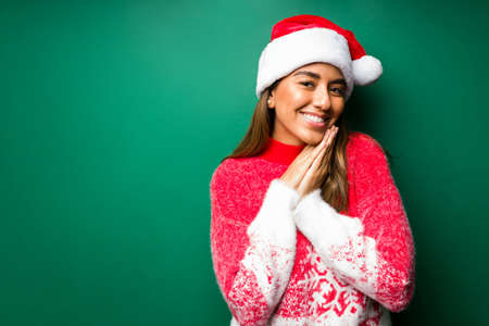 Adorable young woman loving the Christmas holidays and feeling happy against a green backgroundの写真素材