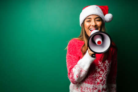 Making a big announcement. Excited young woman talking with a megaphone while celebrating the Christmas holidaysの写真素材