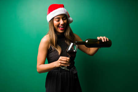 Gorgeous young wpman with a santa hat serving a glass of red wine at a fun Christmas partyの写真素材