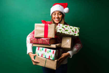 Ready to exchange gifts. Portrait of an attractive woman holding a lot of christmas giftsの写真素材