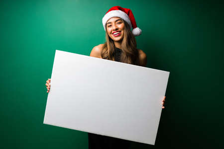Happy latin woman holding a blank sign to make a big announcement and giving a positive messageの写真素材