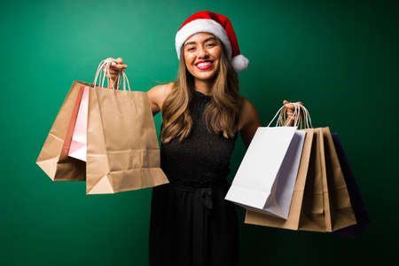 I went Christmas shopping! Happy woman carrying a lot of shopping bags with giftsの写真素材