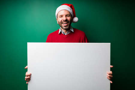 Happy latin man holding a blank sign to make a big announcement and giving a positive messageの写真素材