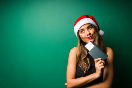 Dreaming of vacations. Smiling hispanic woman holding her plane ticket and ready to travel during the Christmas holidaysの写真素材