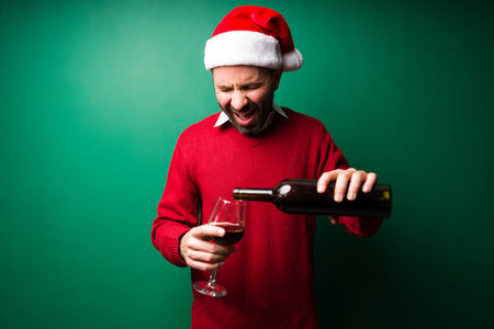 Handsome young man with a santa hat serving a glass of red wine at a fun Christmas partyの写真素材
