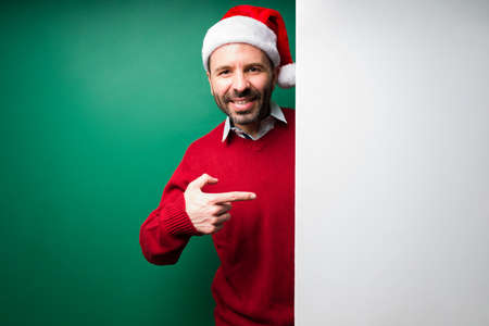 Look at this. Hispanic young man pointing to a blank horizontal ad and smiling against a green backgroundの写真素材