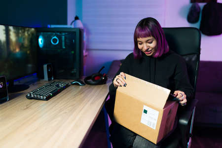 Fast shipping. Cheerful young woman buying new technology and video games while opening the packageの写真素材