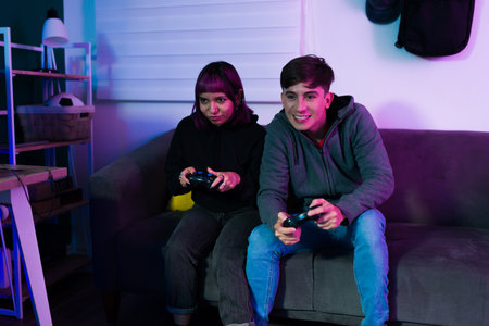 Young woman and man using gamepads while playing together a video game while having fun