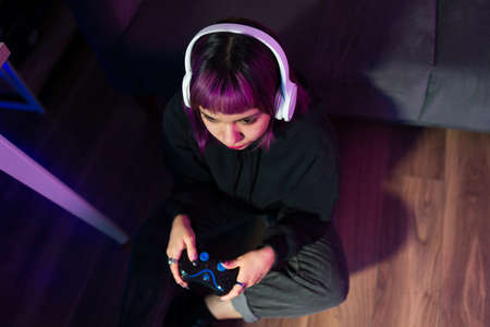 Top view of a young female gamer with headphones concentrated on playing video gamesの写真素材