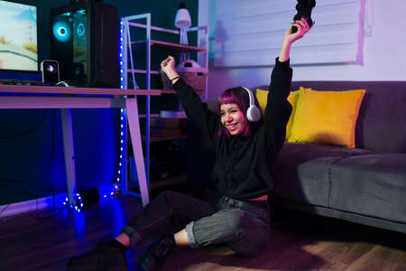 Yes, I'm the winner! Cheerful young woman cheering and celebrating after winning on a video gameの写真素材