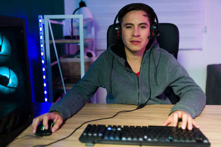 Handsome young man with a headset looking at the camera and playing online video gamesの写真素材