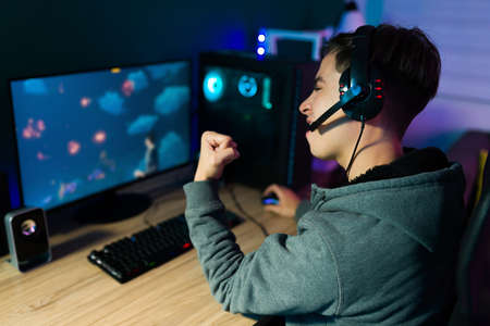 Rear view of a winner young man celebrating and feeling happy after winning an online video competitionの写真素材