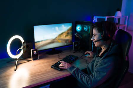 Cheerful handsome gamer recording a video and live streaming while playing online video games at the computerの写真素材