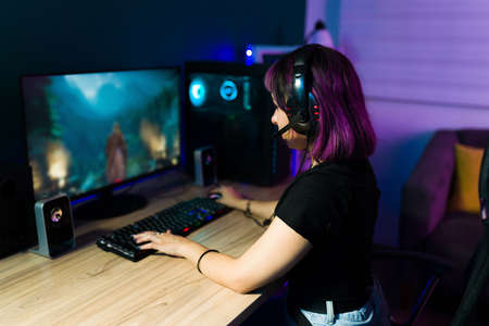 Rear view of a young latin woman sitting at her desk and enjoying an online video gameの写真素材